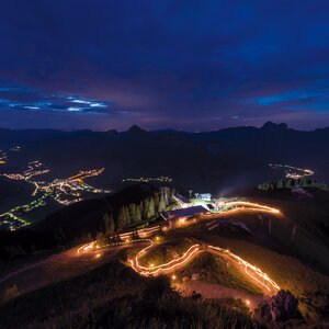 Beleuchteter Serpentinenweg auf dunklem Berg bei Nacht