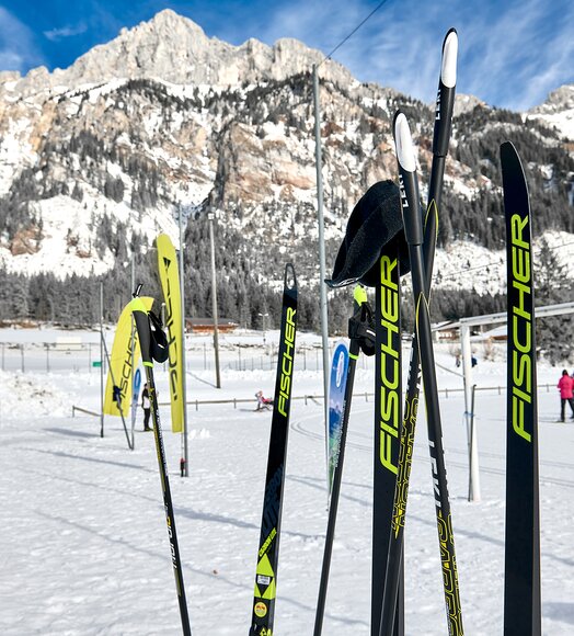 Langlaufski der Marke Fischer im Schnee vor Bergkulisse