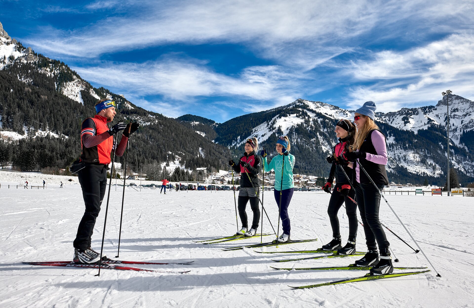 Vier Frauen beim Langlaufen vor Bergkulisse im Winter