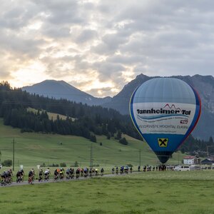 Radfahrergruppe mit Heißluftballon in alpiner Berglandschaft