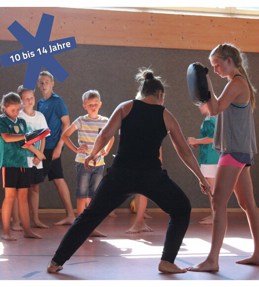 Kinder beim Kampfsporttraining mit Trainer in einer Turnhalle