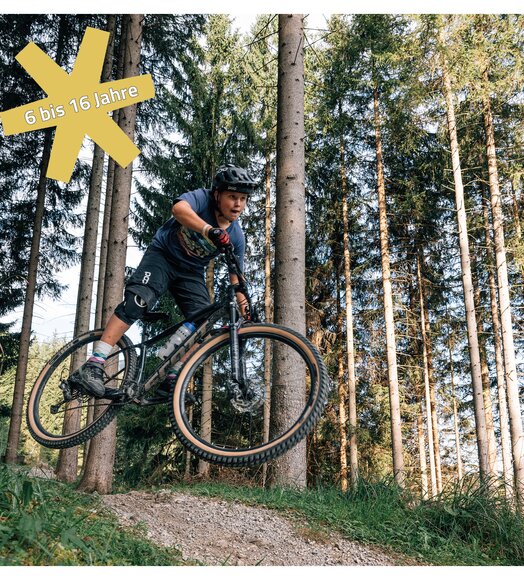 Junge springt mit Mountainbike über Hügel im Wald, gelber Stern mit "6 bis 16 Jahre"