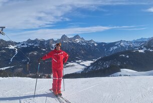 Skifahrer in roter Kleidung vor Bergpanorama im Winter
