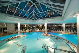 Schwimmbad mit Glasdach und Badegästen
