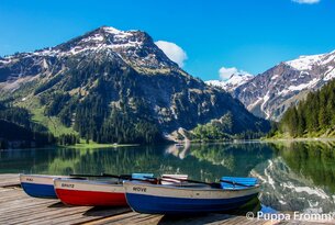 Bergsee mit Spiegelung, zwei Boote im Vordergrund
