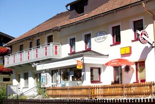 Gasthof Glätzle mit rotem Sonnenschirm und Eiswerbung vor blauem Himmel