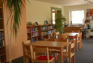 Bibliothek mit Tischen, Stühlen und Bücherregalen