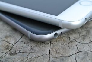Zwei silberne Smartphones übereinander auf rissigem Untergrund