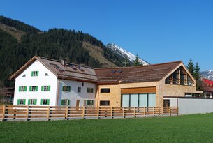 Haus mit Holzzaun vor Berglandschaft
