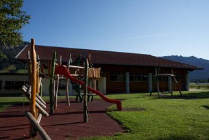 Spielplatz mit Rutsche vor Gebäude mit rotem Dach