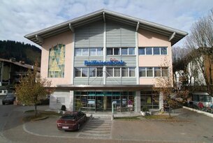 Raiffeisenbank-Gebäude mit Glasfront und Parkplatz bei Tageslicht