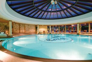 Rundes Schwimmbad mit Glaskuppel und Liegestühlen