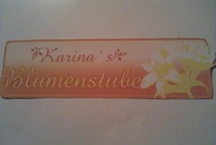 Schild: Karina's Blumenstube mit floralem Dekor auf orangefarbenem Hintergrund