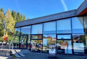 Modernes Gebäude mit Glasfassade und reflektierenden Fenstern bei sonnigem Wetter