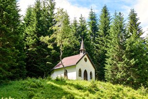 Kleine Kapelle mit rotem Dach am Waldrand