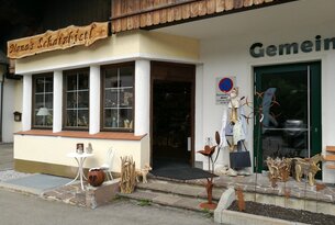 Eingang zu Geschäft mit Schild Schatzkistl, Dekorationen und Skulpturen vor der Tür