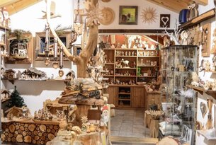 Holzgeschnitzte Figuren und Dekorationen in einem Laden mit Regalen und einem Baumstamm in der Mitte