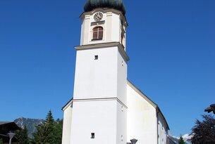 Weiße Kirche mit Zwiebelturm vor blauem Himmel