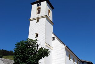 Weiße Kirche mit Kirchturm unter blauem Himmel