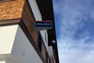 Polizeischild an weißem Gebäude unter blauem Himmel