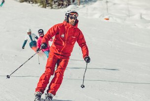 Skifahrer in rotem Anzug fährt auf schneebedeckter Piste