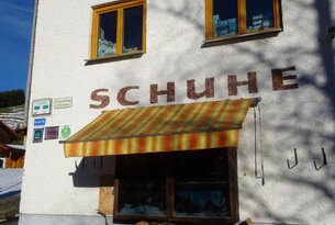 Fassade eines Schuhgeschäfts mit Markise und zwei Fenstern