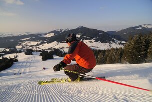 Skifahrer auf Skipiste mit Bergpanorama im Hintergrund