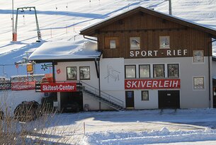 Skiverleih-Gebäude mit Skitest-Center im Schnee vor Skipiste