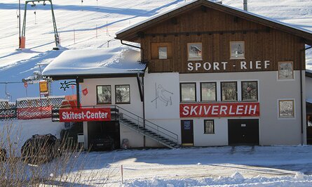Skiverleih-Gebäude mit Skitest-Center im Schnee vor Skipiste