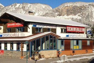 Sportgeschäft Schiverleih vor schneebedeckten Bergen an einem sonnigen Tag