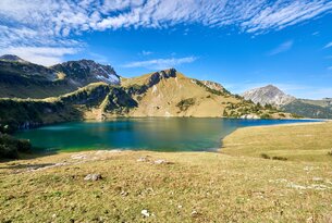 Bergsee mit Bergen im Hintergrund unter blauem Himmel