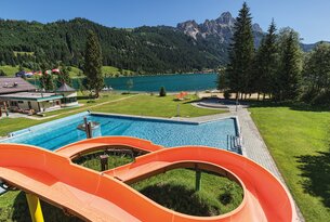 Schwimmbad mit Rutsche vor Bergpanorama und See