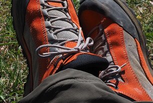Orangefarbene Wanderschuhe auf grünem Gras