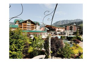 Hotelanlage mit Pool, Garten und Bergen im Hintergrund
