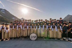 Blaskapelle in Tracht mit Instrumenten vor Bergkulisse