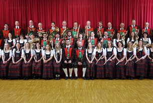 Blasorchester in Tracht vor rotem Vorhang