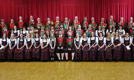 Blasorchester in Tracht vor rotem Vorhang