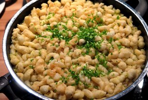 Käsespätzle mit Schnittlauch in einer Pfanne