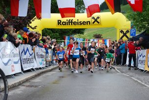 Kinderlauf unter Raiffeisen-Bogen mit Zuschauern am Straßenrand