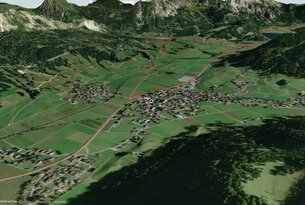 Satellitenansicht einer grünen Landschaft mit Bergen und einer Ortschaft