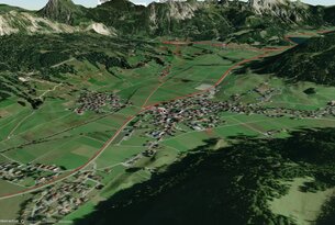 Luftaufnahme einer grünen Landschaft mit Bergen und einer Ortschaft