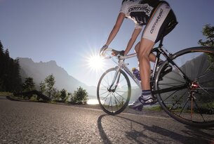 Radfahrer auf Rennrad vor Bergkulisse mit strahlender Sonne