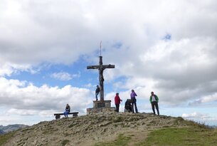 Menschengruppe am Gipfelkreuz auf einem Berg