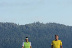 Frau und Mann beim Nordic Walking vor Berglandschaft