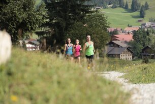 Drei Frauen joggen auf einem Weg in ländlicher Umgebung