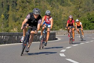 Radrennfahrer in Helmen fahren auf einer kurvigen Straße bergauf