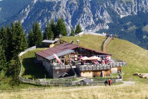 Berghütte mit Terrasse vor Bergpanorama
