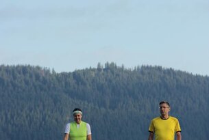 Zwei Personen beim Nordic Walking vor Berglandschaft