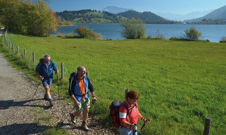 Wanderer auf Pfad mit See und Bergen im Hintergrund