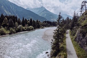 Fluss schlängelt sich durch grüne Landschaft, Berge im Hintergrund